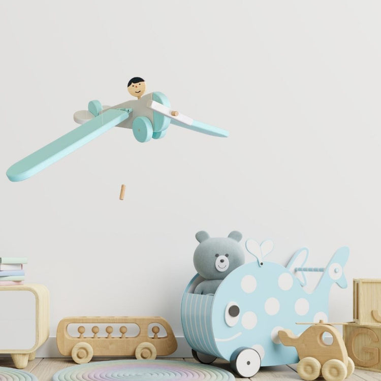 Handmade wooden airplane mobile styled in a soft nursery setting