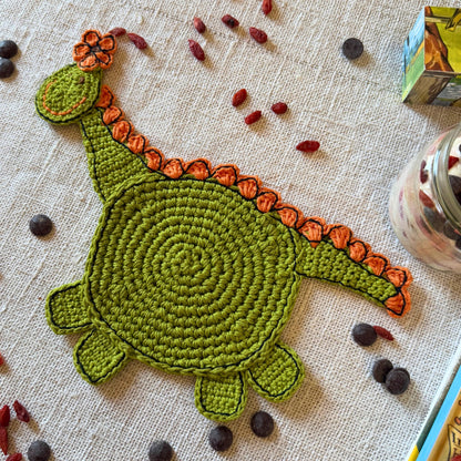 Full green crochet dinosaur with a round body, long neck, legs and tail