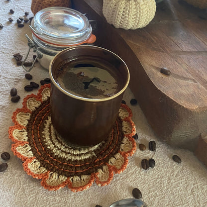 Coffee cup on a textured coaster with coffee beans around on a wooden surface