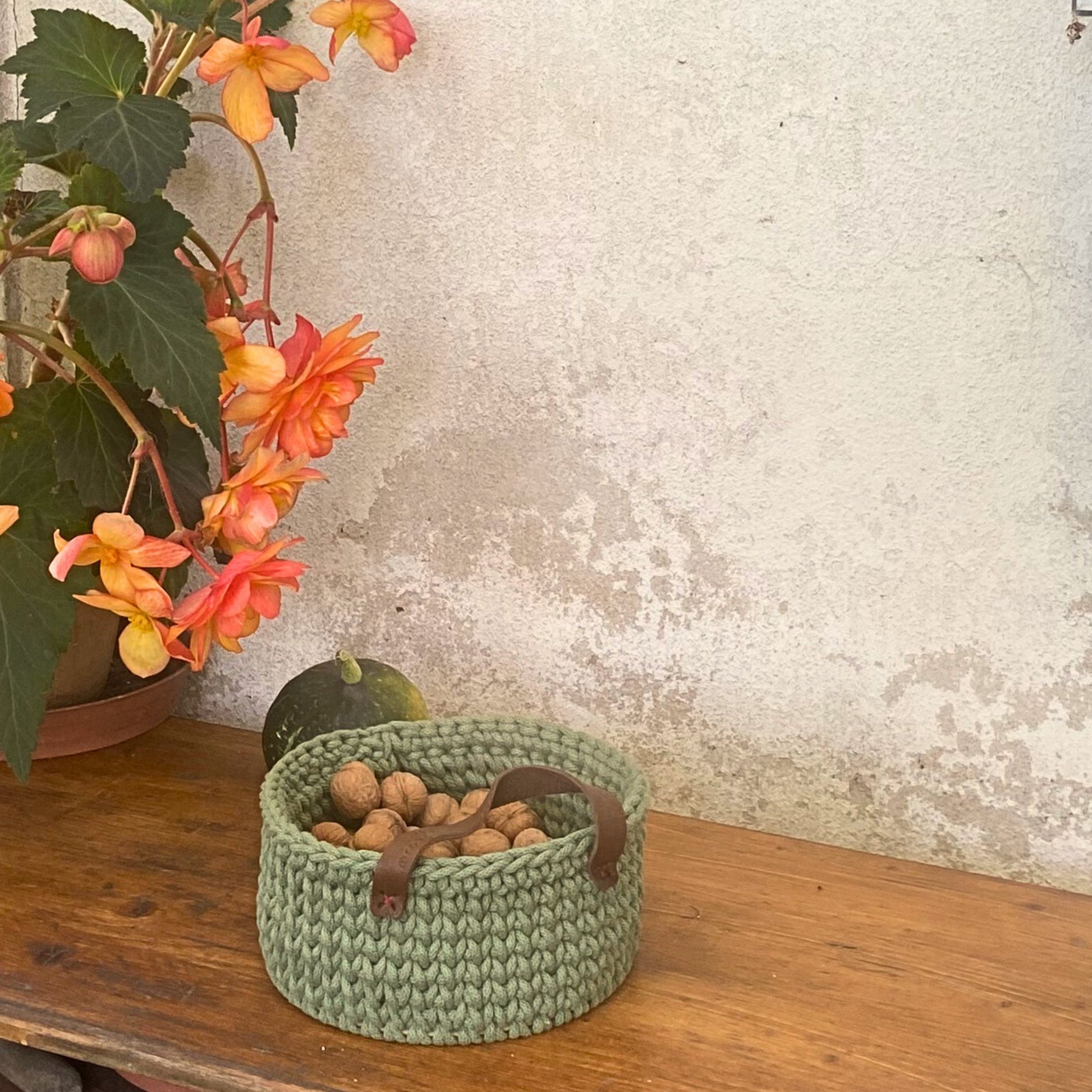Small green crochet storage basket on wooden table